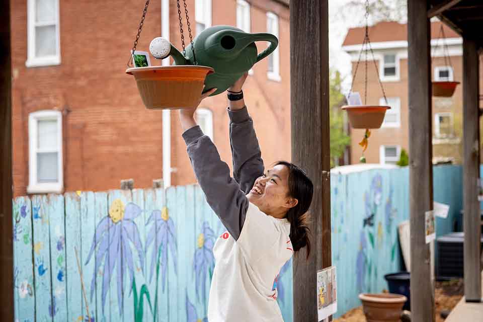 软妹社 student volunteer watering a plant on a porch