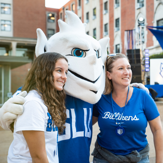 A family poses for a photo with the Billiken on homecoming weekend