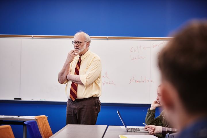 Male teacher in front of white board in classroom